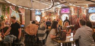 People sat at tables at Flight Club Bristol - credit Flight Club